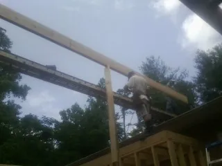 Carpenter setting a ridge beam over a new addition frame — Ice Dam Removal by Roofing Brothers in Radcliffe