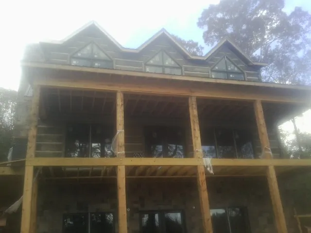 Dormers and porch framing on a large log home under construction — Roof Coating work by our crew in Radcliffe