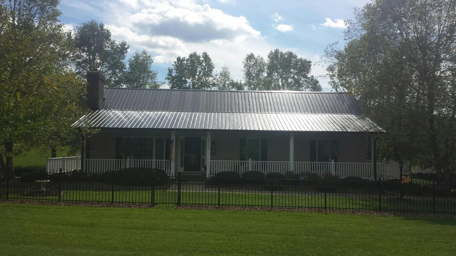 Gray metal roof on a brick ranch with a full width front porch — Gutter Guard Installation work by our crew in Radcliffe