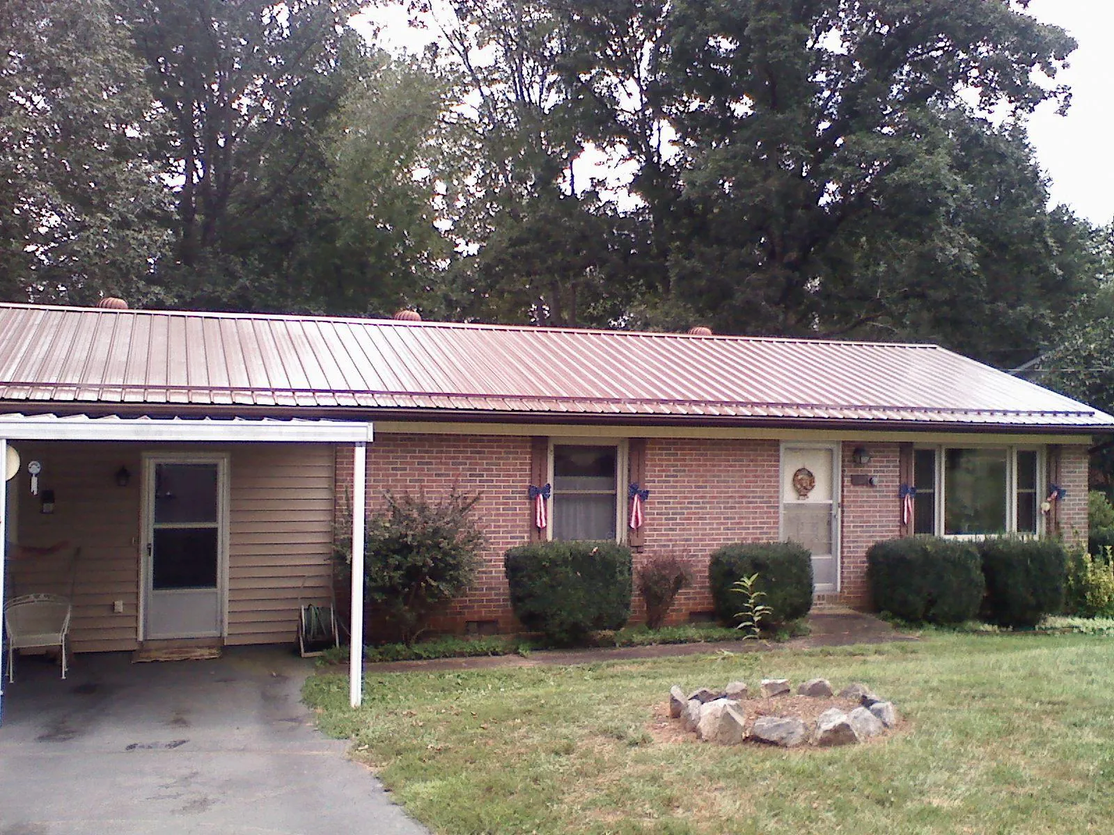 Bronze metal roof and carport on a brick ranch home — Roof Repair work by our crew in Radcliffe