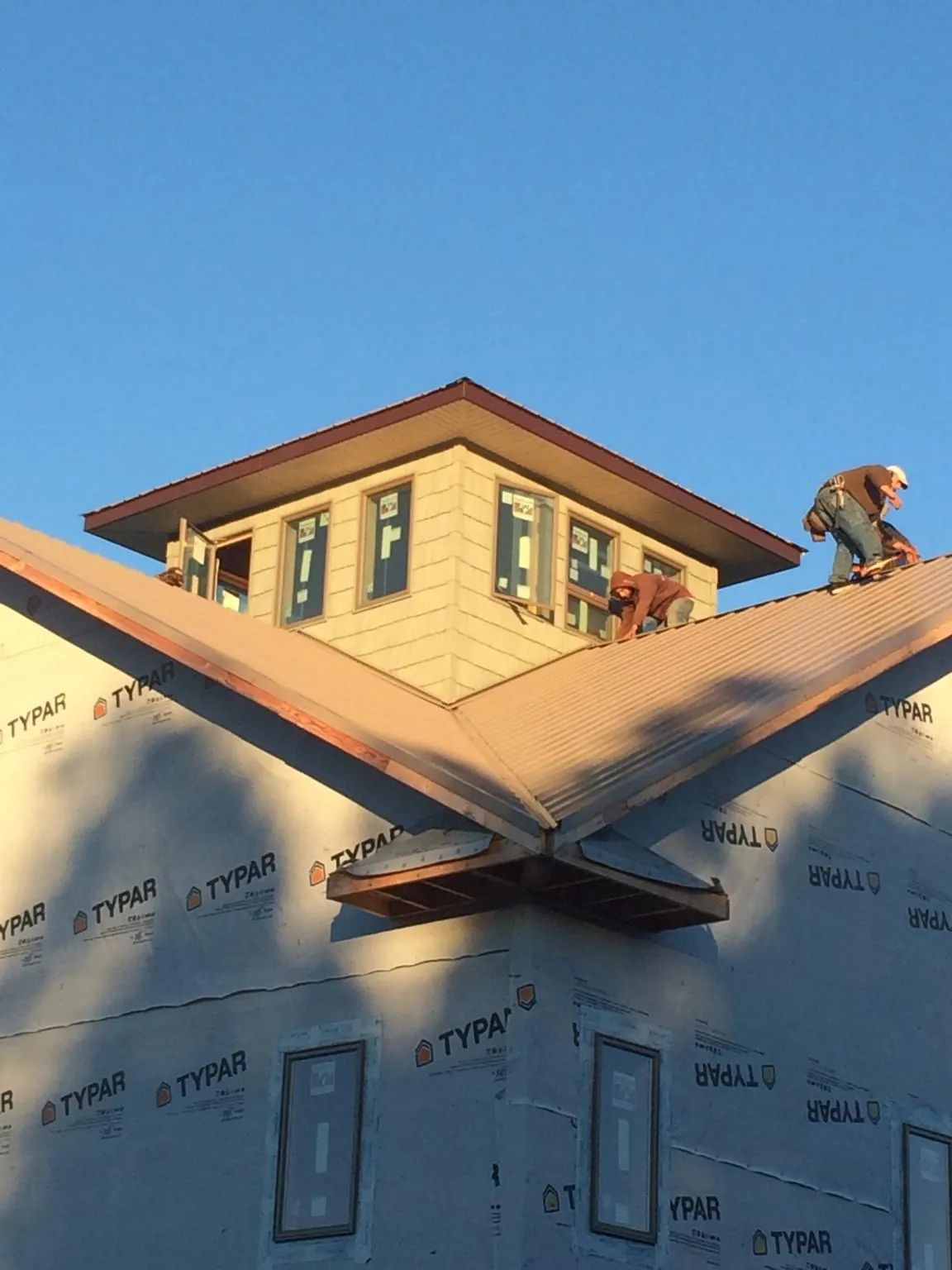 Roofers working around a rooftop cupola on a new metal roof at sunset — Roof Waterproofing in Radcliffe by Roofing Brothers